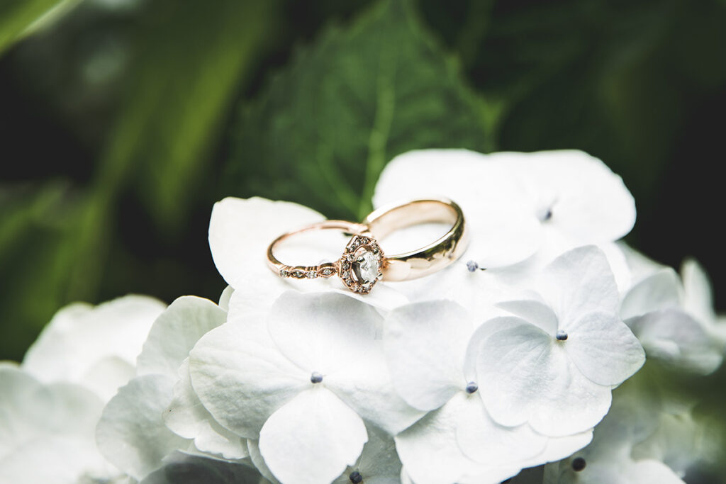 gold wedding rings on white flowers by Kiriell Visuals