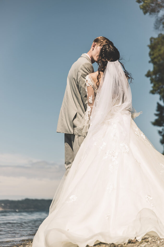 bride and groom kiss by the beach by Kiriell Visuals