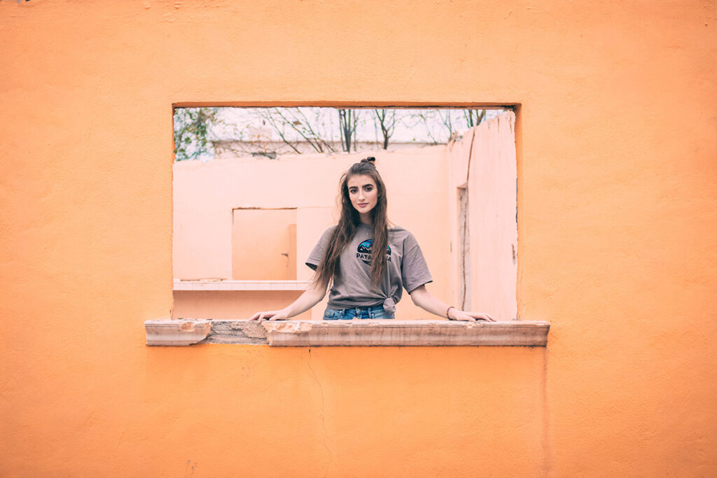 girl looking out the window of orange wall by Kiriell Visuals